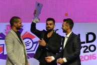 Indian cricketers Shikhar Dhawan (L) and Ajinkya Rahane (R) smile as Virat Kohli holds the ICC World Twenty20 India 2016 trophy during an event to announce the groups and schedule, in Mumbai, in December 2015