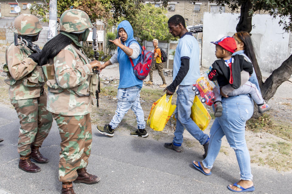 Soldiers interact with resident while on patrol in Mannenburg, Cape Town, South Africa Saturday, March 28, 2020. South Africa went into a nationwide lockdown to restrict public movements for 21 days in an effort to control the spread of the virulent COVID-19 coronavirus.(AP Photo)