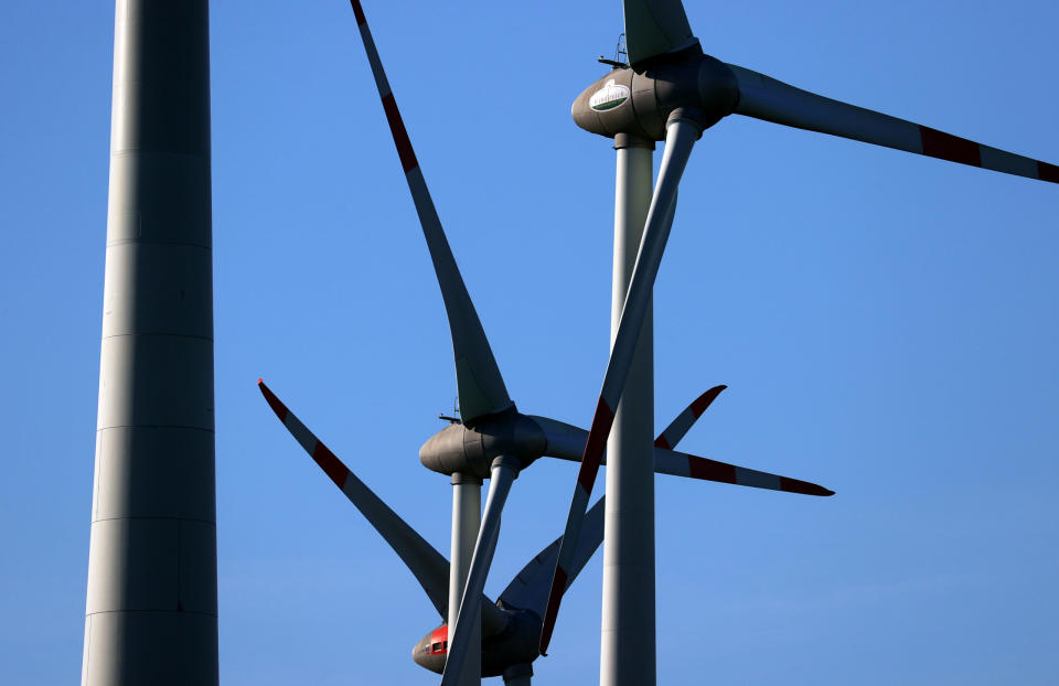 Windräder drehen sich vor blauem Himmel.