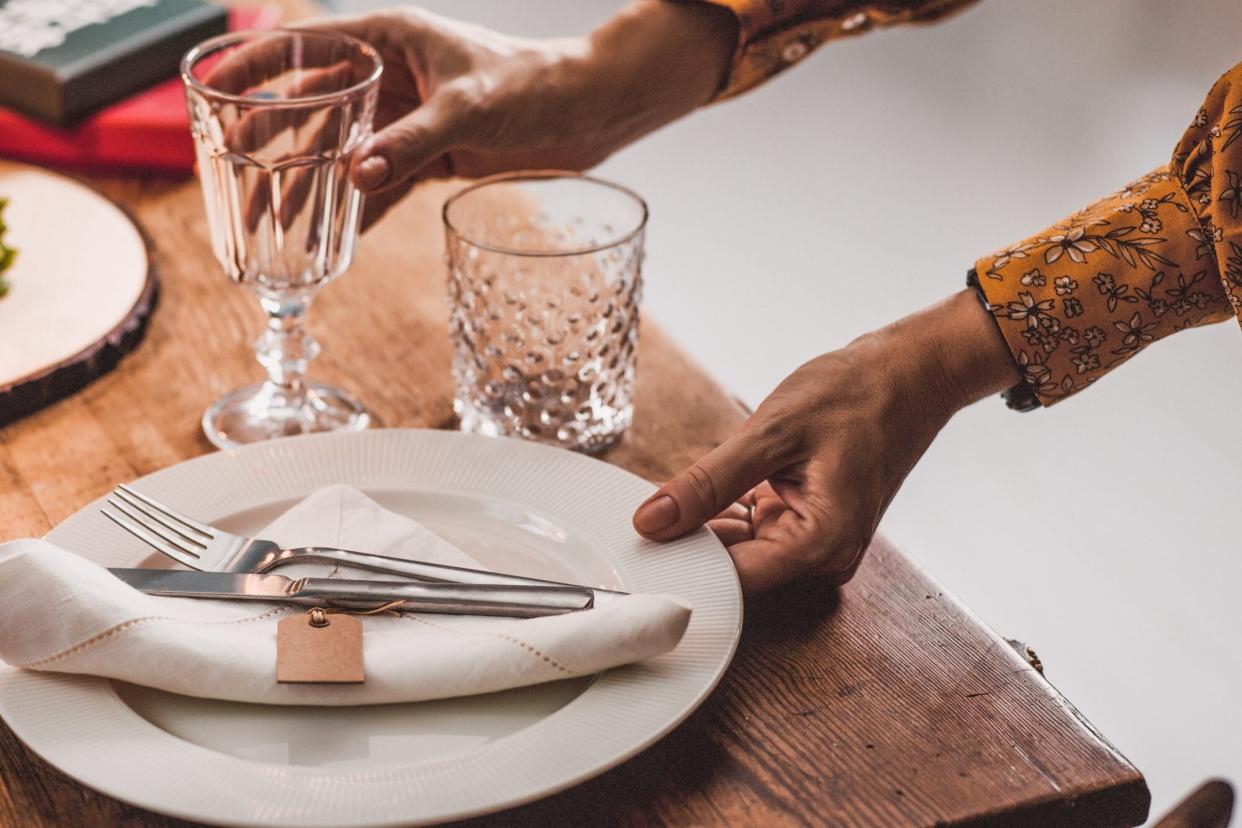 A woman setting the table for a dinner party. (Getty Images)