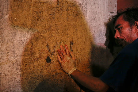 A funeral parlour worker, his hands bloodied from carrying bodies, rests against the wall of a house in Manila, Philippines early November 1, 2016. According to police and witnesses, unknown masked gunmen killed five people inside the house that is a known drug den. REUTERS/Damir Sagolj