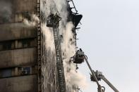 <p>Iranische Feuerwehrleute versuchen, die Flammen im eingestürzten Plasco-Gebäude in Teheran zu löschen. (Bild: Vahid Salemi/ AP) </p>