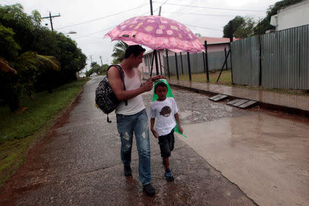A man holds a umbrella against the rain as he walk with a boy to shelter prior to the arrival of hurricane Otto in Bluefields, Nicaragua November 24, 2016. REUTERS/Oswaldo Rivas