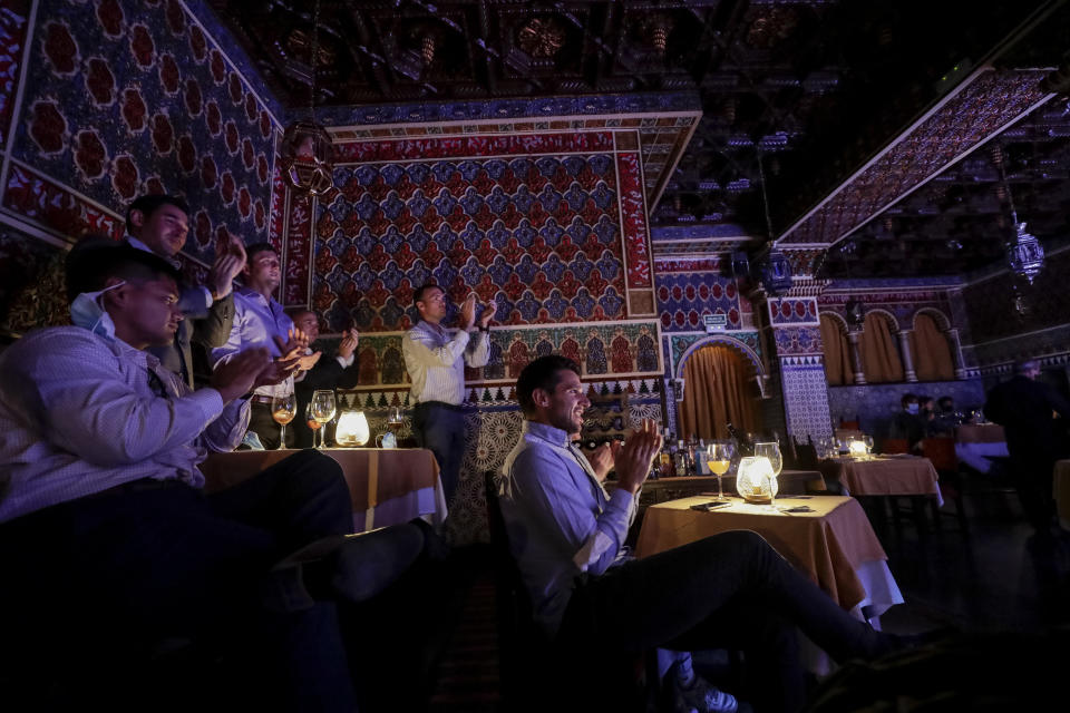 People applaud at the end of a flamenco show at the Torres Bermejas "tablao," or live flamenco venue, in Madrid, Spain, Friday, Sept. 25, 2020. The passion and drama of live flamenco shows are back on stage in Madrid. But now the performers are behind Perspex screens and keeping their distance from the audience. The Torres Bermejas “tablao,” or live flamenco venue, has reopened its doors to customers after seven months closed due to the COVID-19 pandemic. (AP Photo/Manu Fernandez)