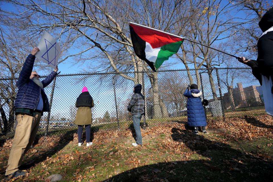 David Bildner holds up a sign with the Star of David on it as a woman waves a Palestinian flag, outside Teaneck High School, Wednesday, November 29, 2023. Both people were standing outside Teaneck High School when a group of students walked out to protest the war in the Middle East.