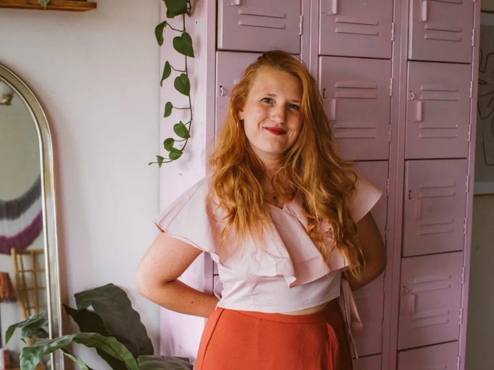 Kara Harms stands in her apartment with house plants