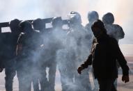 A man walks next to police officers among tear gas during a protest against Brazilian President Jair Bolsonaro in Sao Paulo