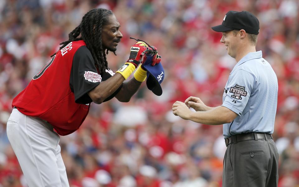 The umpire returns Snoop Dogg's glasses after he was found safe at second base during the Legends and Celebrity Softball game, Sunday, July 12, 2015, at Great American Ball Park.