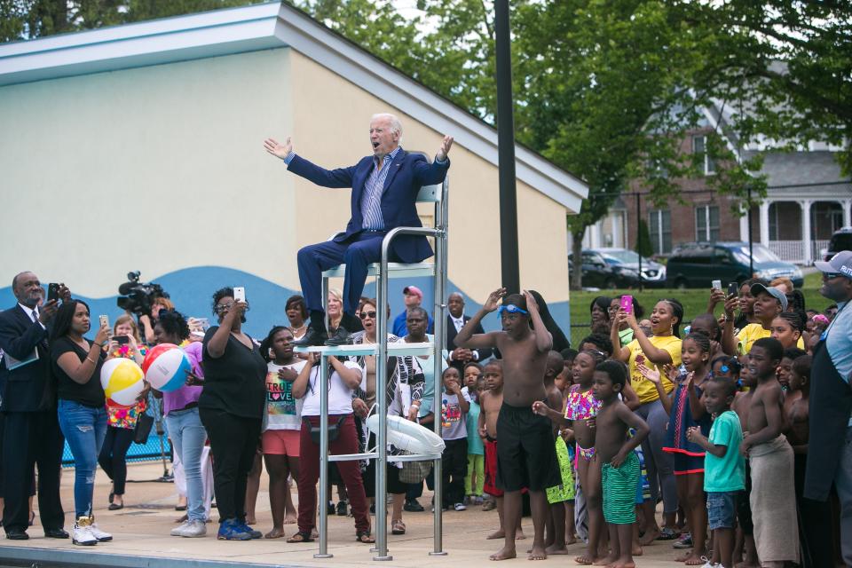 Former Vice President Joe Biden sits in the lifeguard chair and cheers along with the crowd as they reveal the renaming of the pool facility being dedicated in his honor to the Joseph R. Biden Jr. Aquatic Center in Wilmington, Del.