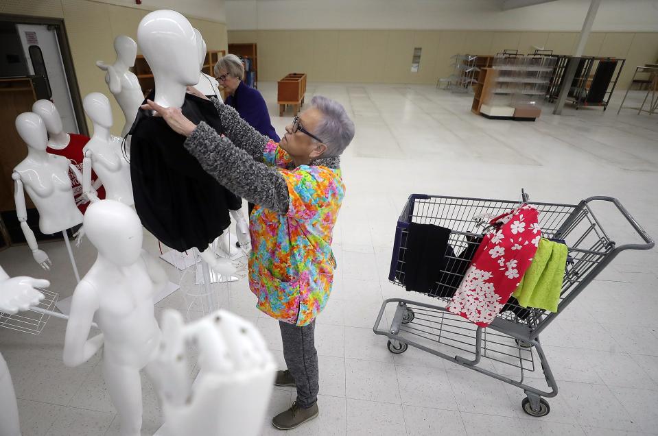 Volunteer Mona Santos pulls a dress over the head of a mannequin as she helps get the boutique section of the new St Vincent de Paul Super Store ready on Wednesday, Mar. 1, 2023.