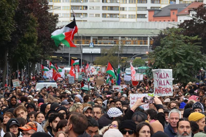 Participants hold up signs and Palestinian flags during the rally "Demo against genocide in Gaza" meeting in Berlin. Joerg Carstensen/dpa