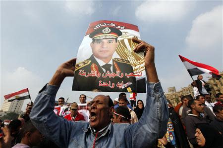 A supporter of Egypt's army chief General Abdel Fattah al-Sisi holds up a poster of Sisi at Tahrir square in downtown Cairo, November 19, 2013, during a rally to commemorate the second anniversary of the deaths of 42 people in clashes with security forces on Mohamed Mahmoud Street nearby. REUTERS/Mohamed Abd El Ghany