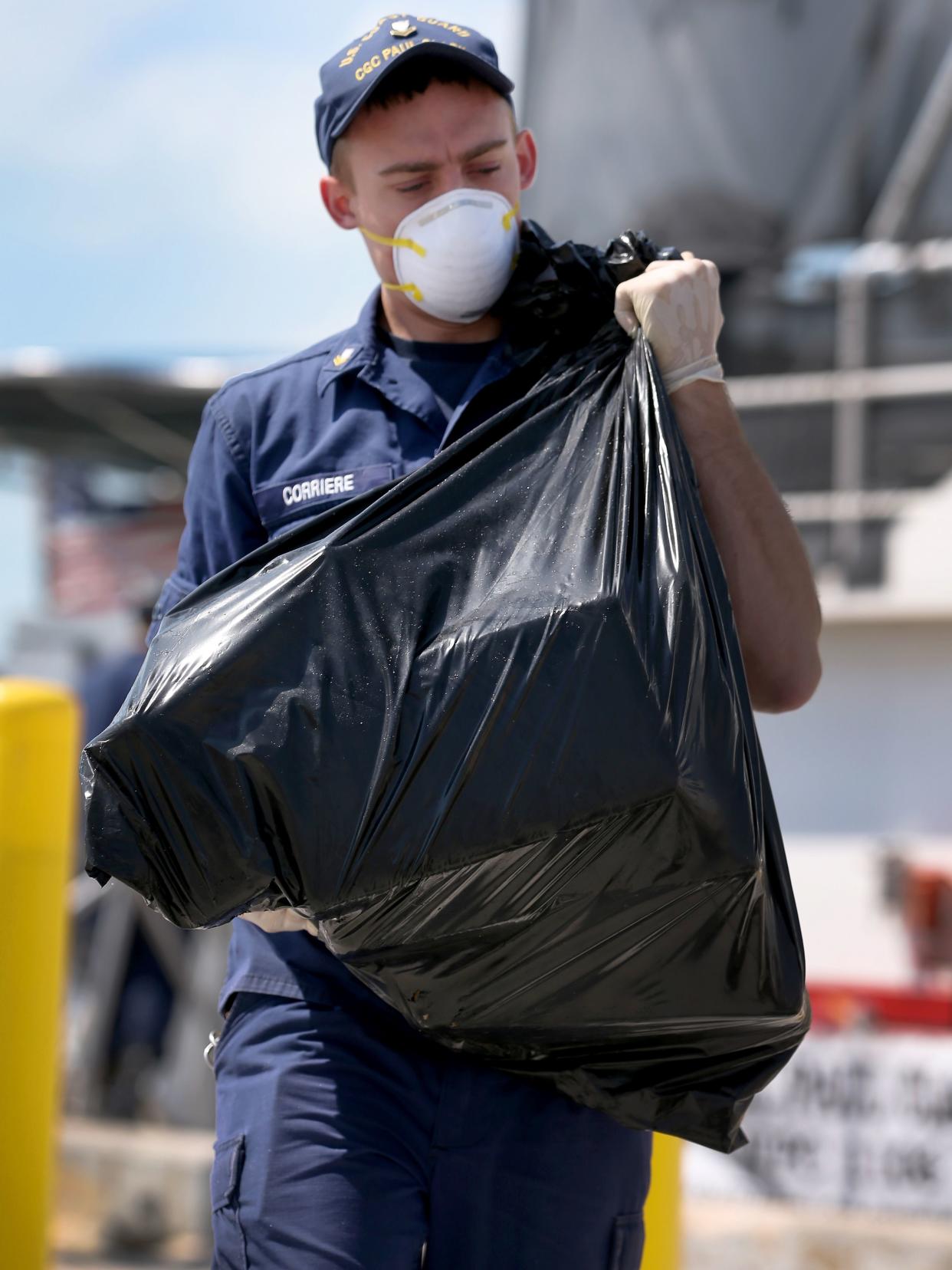  A U.S. Coast Guard crew member carries a bag full of blocks of marijuana from the Paul Clark one of the Coast Guard's newest fast-response cutters on May 9, 2014 in Miami Beach, Florida.