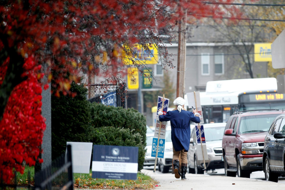 Patrick Coleman, a candidate for state representative, walks down the street with signs for himself, U.S. House of Representatives candidate Eddie Edwards, and others, in Dover, New Hampshire.&nbsp;