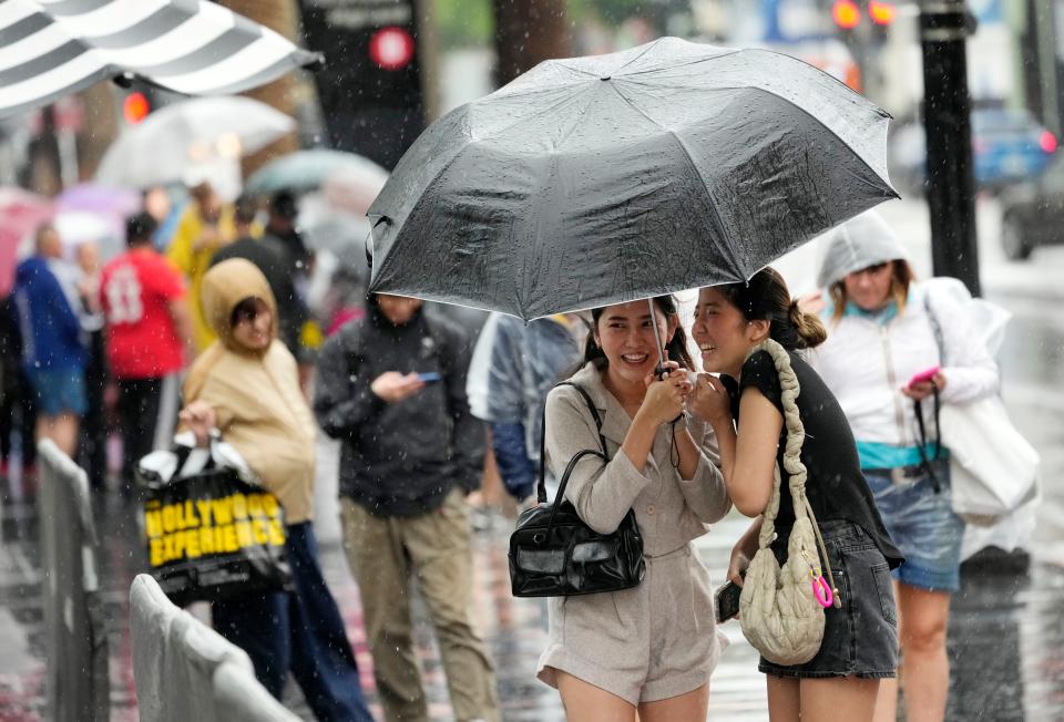 Pedestrians with umbrellas shield themselves from wind and rain on Hollywood Boulevard during Tropical Storm Hilary, Sunday, Aug. 20, 2023, in Los Angeles. (AP Photo/Chris Pizzello)