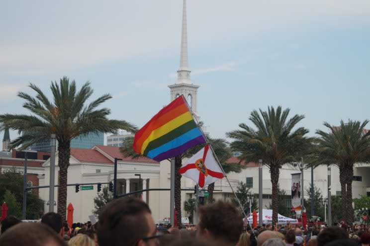 A gay pride flag and a Florida state flag wave at a vigil outside the Dr. Phillips Center for the Performing Arts in downtown Orlando on Monday. (Photo: Michael Walsh/Yahoo News)