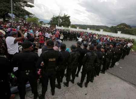 Guatemalan police officers watch as Honduran migrants, part of a caravan trying to reach the U.S., arrive in Esquipulas city in Guatemala, October 15, 2018. REUTERS/Jorge Cabrera