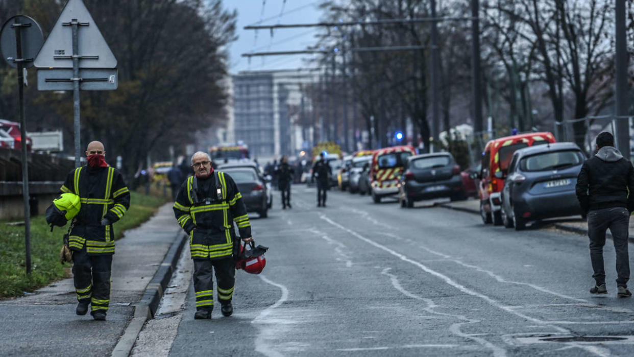 firefighters walk in the Mas-Du-Taureau neighbourhood  where a fire caused many victims, in Vaulx-en-Velin, east of Lyon, south-eastern France, on December 16, 2022. - A fire in a building near Lyon in central-eastern France killed ten people, including five children, and injured fourteen, four of them seriously, on the night of December 15, 2022, the prefecture said. The fire, whose 