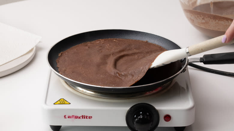 flipping chocolate crepe in a pan