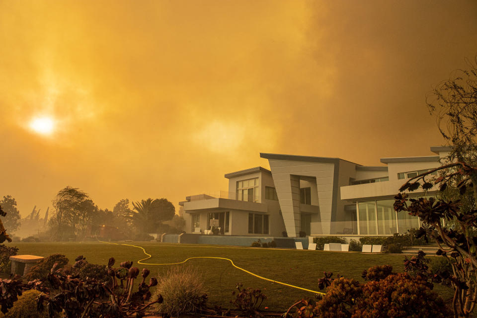 A single fire hose crosses artificial grass in the backyard of a house on Hidden Glen Lane after the Green Fire passed by in Yorba Linda, Calif., Monday, Oct. 26, 2020 (Leonard Ortiz/The Orange County Register via AP)