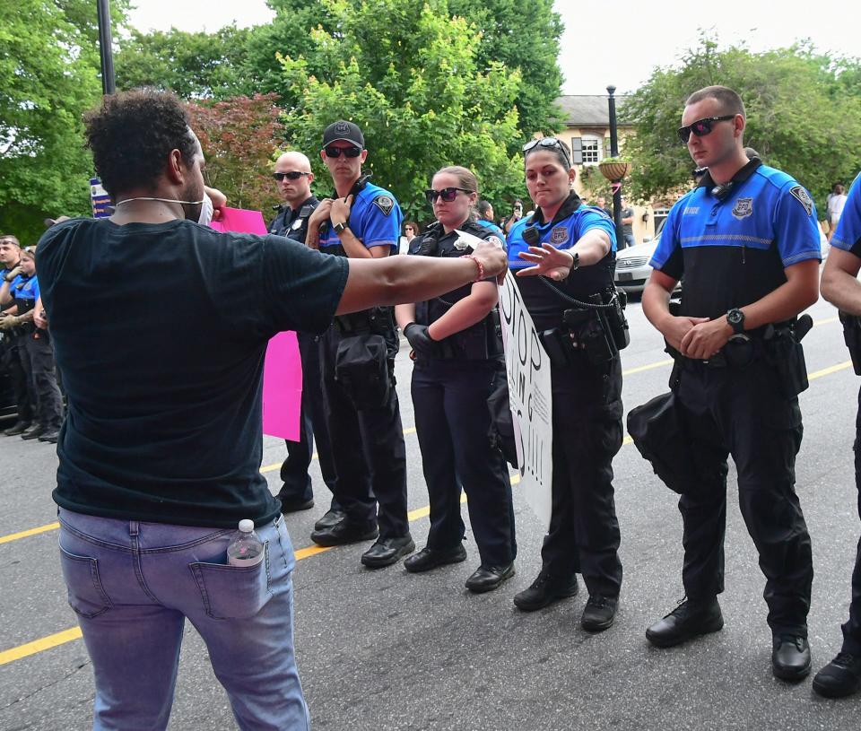 Greenville police S.N. Bowdoin, right, holds a "No Justice No Peace" sign protester Taurice Bussey, left, gave her during a protest remembering George Floyd at Falls Park in Greenville Sunday, May  31, 2020.