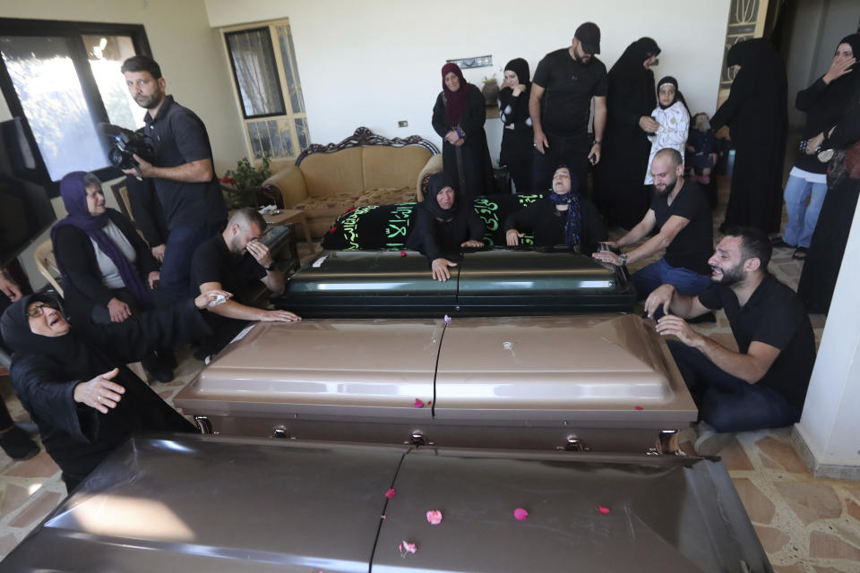 Relatives of the victims weep over the coffins in the town of Ainata, a Lebanese border village with Israel in south Lebanon, Tuesday, Nov. 7, 2023. A Lebanese woman and her three grand daughters were laid to rest in their hometown in southern Lebanon two days after they were killed in an Israeli drone strike while in a car near the Lebanon-Israel border. (AP Photo/Mohammed Zaatari)