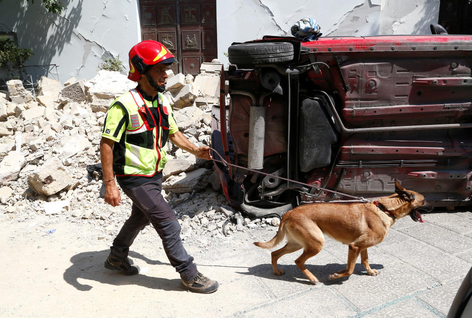 <p>A rescue worker inspects with a dog the damaged area after an earthquake hits the island of Ischia, off the coast of Naples, Italy, Aug. 22, 2017. (Photo: Ciro De Luca/Reuters) </p>