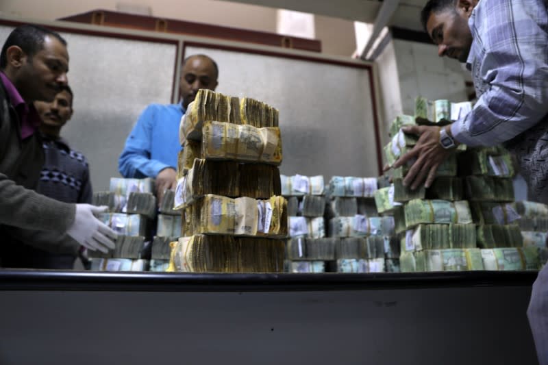 Employees count bundles of newly issued Yemeni Riyal bank notes at the Central Bank of Yemen in Sanaa