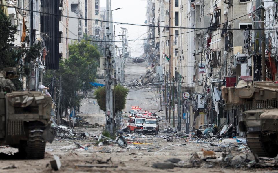 A convoy of Palestinian ambulances waits on a road leading to Al Shifa Hospital in Gaza City