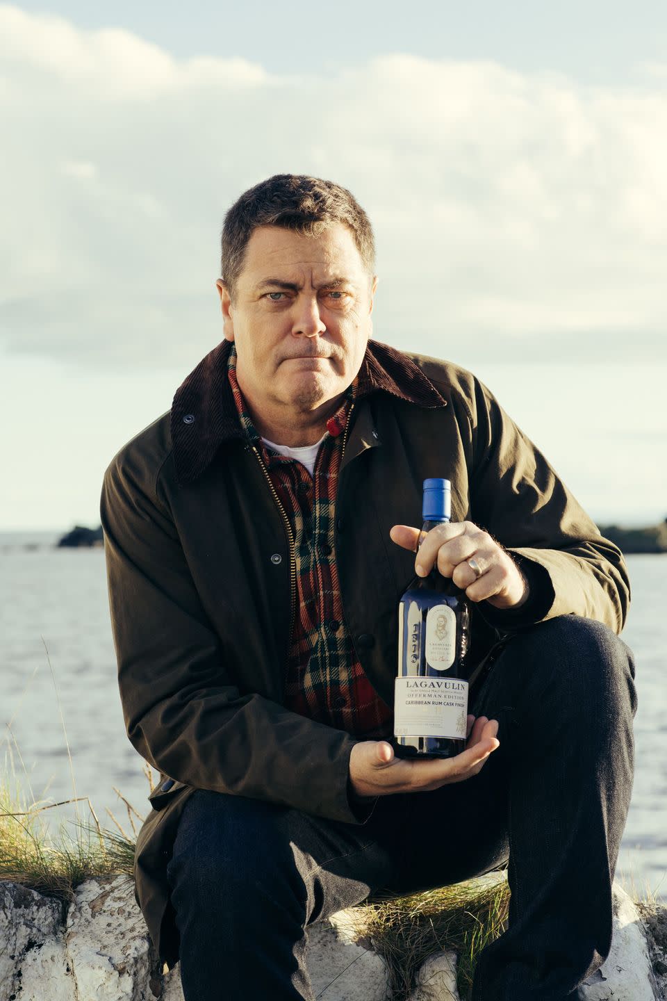 a man sitting on a rock holding a bottle of alcohol