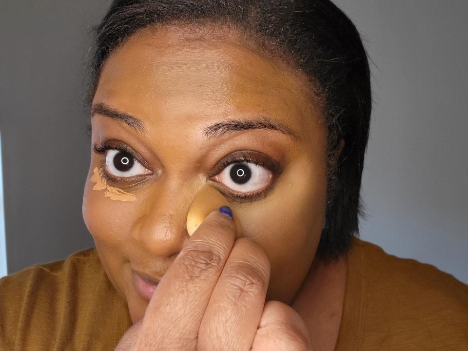 The writer applies concealer on her under eyes with a sponge