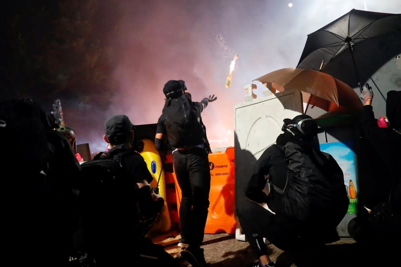 Anti-government protesters take cover during a standoff with riot police at the Chinese University of Hong Kong, in Hong Kong