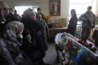Relatives gather next to the body of 29 year old Yana Rikhlitska, a Ukrainian army medic killed in the Bakhmut area, during the funeral in Vinnytsia, Ukraine, Tuesday, March 7, 2023. Just over a week ago, Yana Rikhlitska was filmed by The Associated Press as she helped treat wounded soldiers in a field hospital of Bakhmut area which has been pulverized as Russia presses a three-sided assault to seize it. (AP Photo/Thibault Camus)