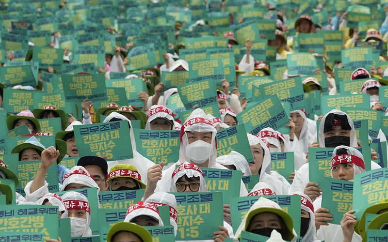 Members of the Korean Health and Medical Workers' Union hold up green signs during a rally