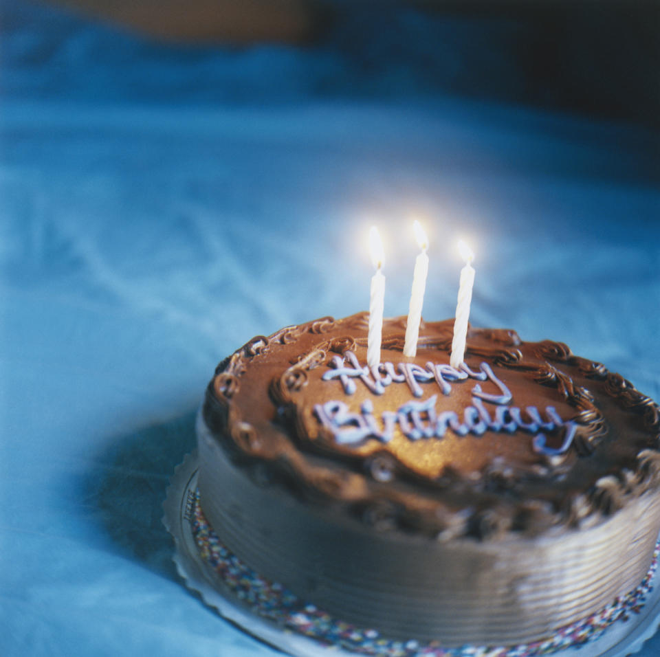 A birthday cake with lit candles and "Happy Birthday" icing text