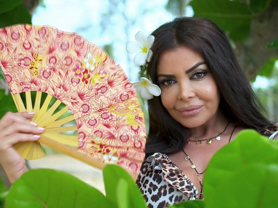 Kader Loth hält einen Fächer in der Hand, Blumen im Haar