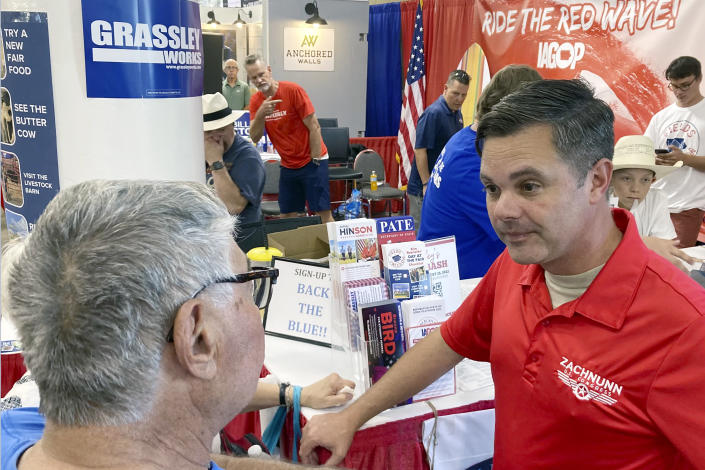 Iowa Republican candidate for Congress Zach Nunn, right, listens to Arvin Foell of Kelley, Iowa, while visiting the Iowa Republican Party booth at the Iowa State Fair in Des Moines, Iowa, August 12, 2022. Nunn is among more than a dozen strict abortion opponents running in competitive House, Senate and governor races working to soften his profile in light of increased enthusiasm among Democratic voters since the June U.S. Supreme Court decision reversing a federal right to abortion. (AP Photo/Thomas Beaumont)