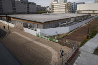 A guard walks around a closed building complex being built as part of the athletes' village to be used during the postponed Tokyo 2020 Olympic and Paralympic Games, in Tokyo Thursday, April 8, 2021. Many preparations are still up in the air as organizers try to figure out how to hold the postponed games in the middle of a pandemic. (AP Photo/Hiro Komae)