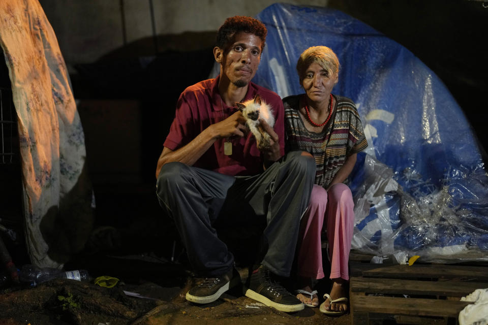Homeless couple Eduardo Pedro da Costa, 24, and Aparecida da Costa, 38, pose for a photo outside the tent where they live on the sidewalk in downtown Sao Paulo, Brazil, Wednesday, Jan. 26, 2022. The homeless population in Sao Paulo has increased 30% during the COVID-19 pandemic, a new census shows. (AP Photo/Andre Penner)