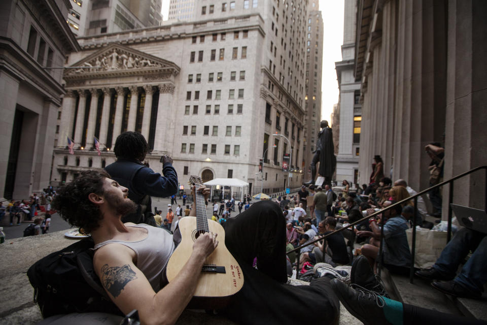 A member of the Occupy movement plays his guitar while resting on the steps of Federal Hall near the New York Stock Exchange in New York, April 16, 2012. REUTERS/Lucas Jackson