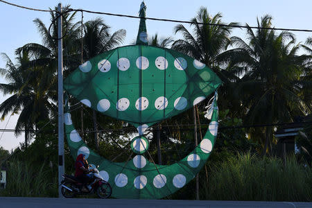 A motorcyclist passes a Parti Islam Se-Malaysia (Malaysian Islamic Party) wau or traditional kite in Kota Bharu, Kelantan, Malaysia April 12, 2018. Picture taken April 12, 2018. REUTERS/Stringer