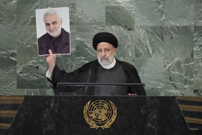 President of Iran Ebrahim Raisi holds up a photo of slain Iranian Gen. Qassem Soleimani as he addresses the 77th session of the United Nations General Assembly, Wednesday, Sept. 21, 2022 at U.N. headquarters. (AP Photo/Mary Altaffer)