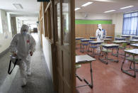 Workers wearing protective gear disinfect as a precaution against the new coronavirus in a class at a high school in Busan, South Korea, Saturday, May 30, 2020. (Jo Jung-ho/Yonhap via AP)