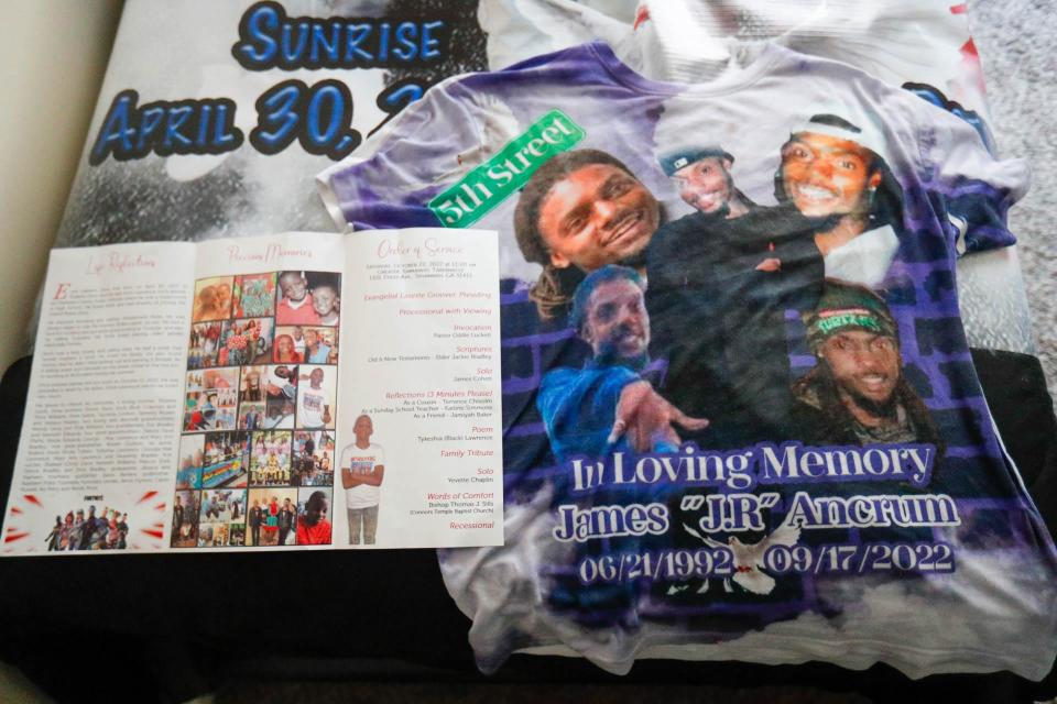 A memorial book from Erick's funeral is on Erick's bed next to a t-shirt with a memorial to his cousin James Ancrum, who was also killed recently.