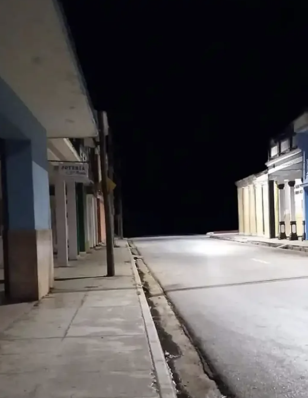 Nighttime view of a deserted street lined with closed shopfronts