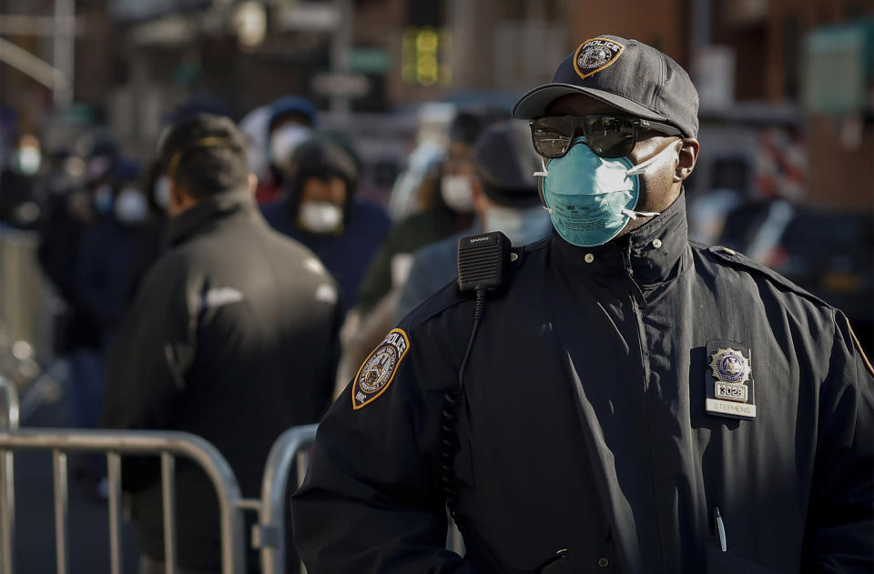 A New York City police officer wears protective gear while monitoring people waiting in line to be tested for the coronavirus outside Elmhurst Hospital in Queens on March 26. (Photo: Stefan Jeremiah / Reuters)