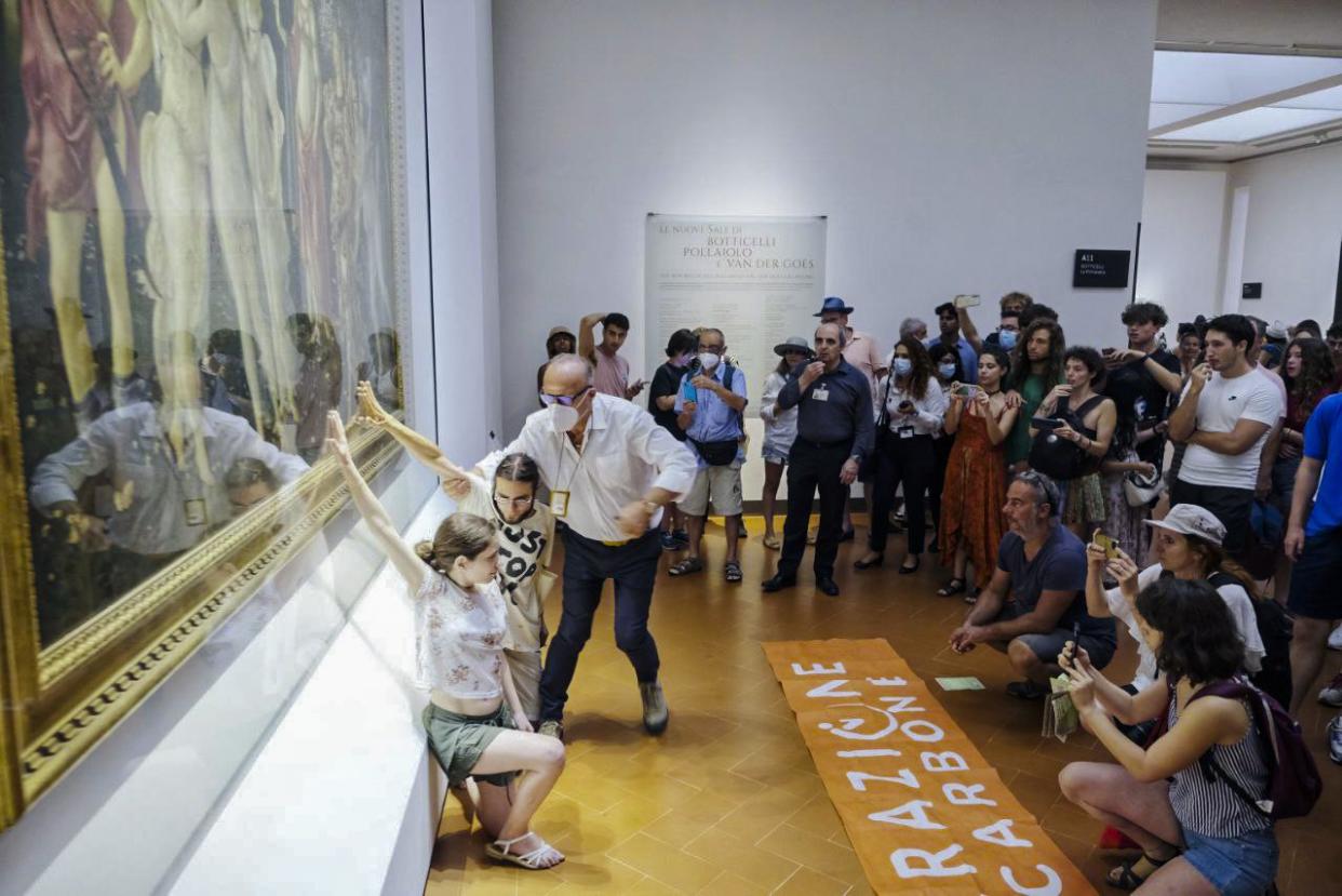 A museum's official tries to block two activists of Ultima Generazione (Last Generation) environmentalist group as they try to glue themselves to the glass protecting Italian Renaissance painter Sandro Botticelli's Primavera (Spring) in Florence. (Ultima Generation via AP)