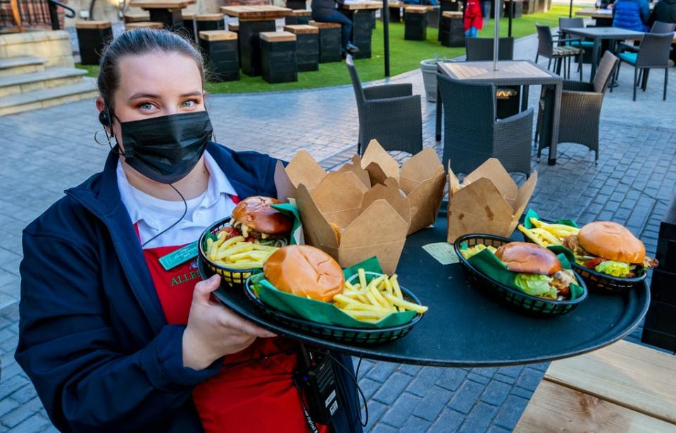 A member of staff carries a tray of food at Allerton Manor golf course in Liverpool (Peter Byrne/PA) (PA Archive)