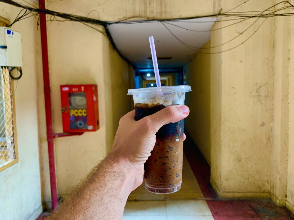 Hand holding up a cup of iced Vietnamese coffee