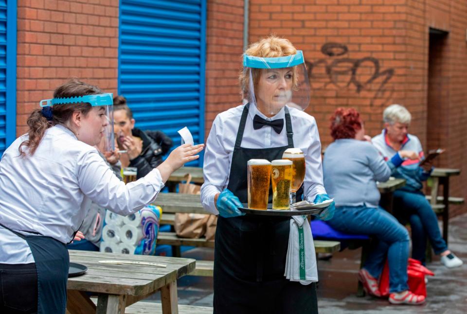 Staff wearing PPE serve people enjoying a drink in Belfast city centre on Friday: AFP/Getty